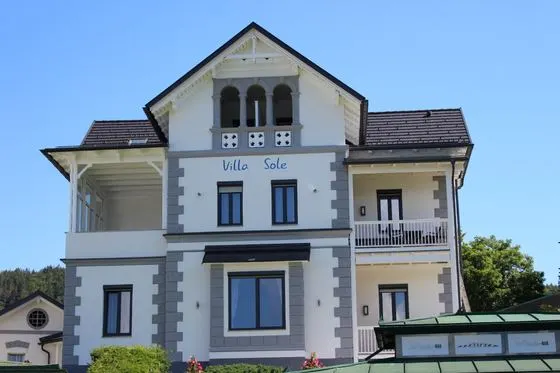 Die Villa Sole von der Straßenseite: weiße Jugendstilfassade mit Loggia, Balkonen und dem Schriftzug Villa Sole